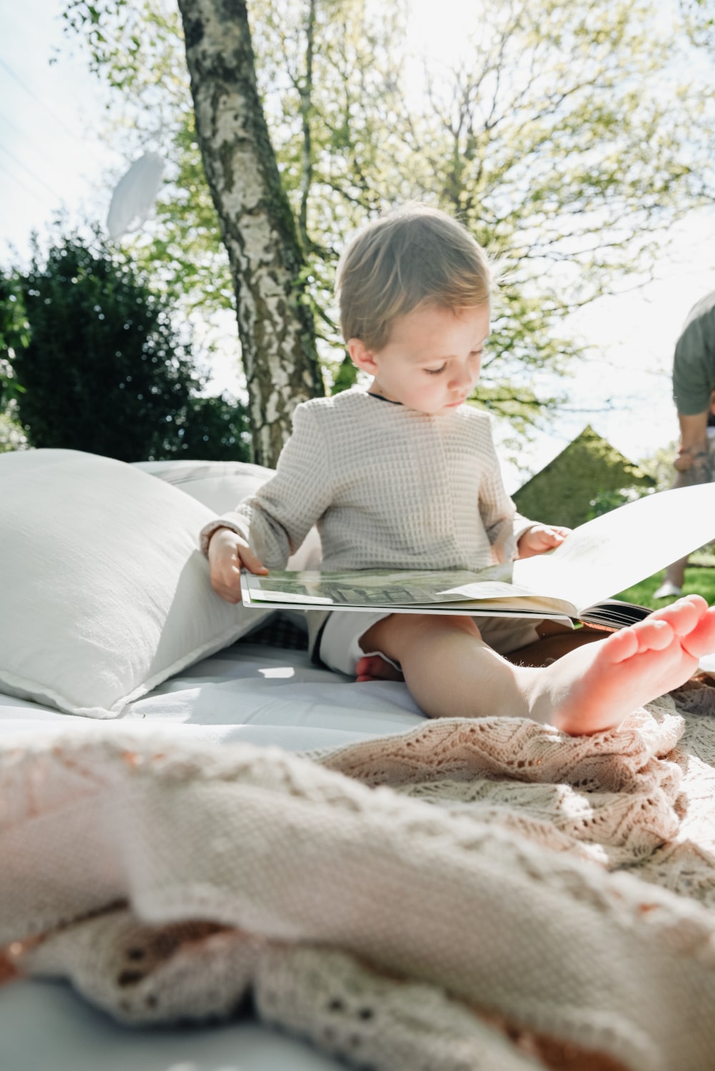 Un enfant lisant un livre à l'ombre d'un arbre pour illustrer la lecture de ma newsletter