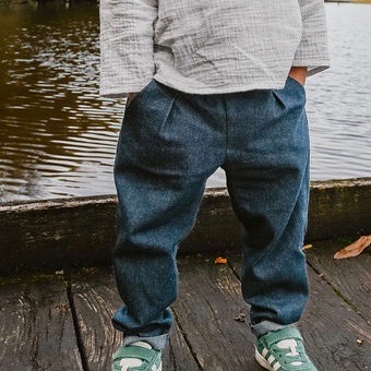 Jean baggy enfant en denim brut bleu foncé, coupe ample avec pinces à la taille, style bohème, porté avec une blouse en double gaze de coton