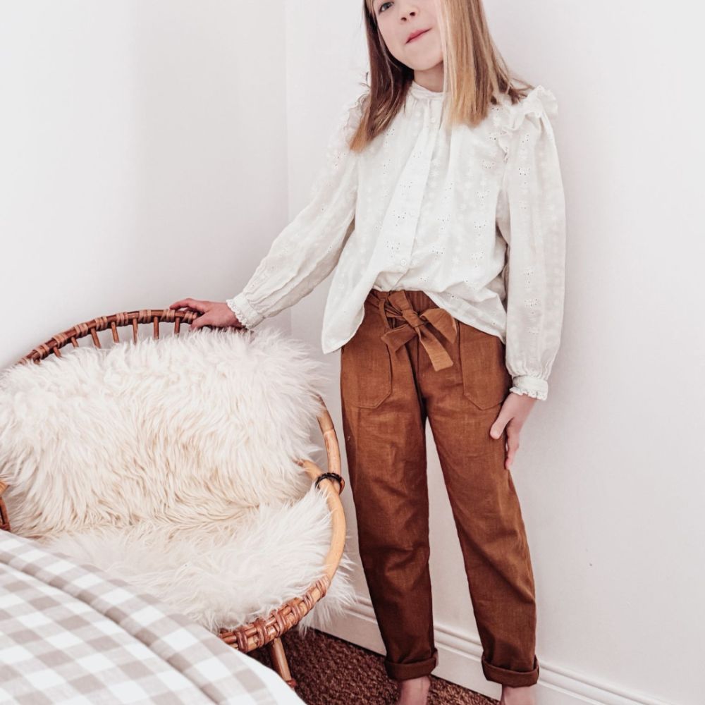 Fille de 10 ans vêtue d'un pantalon en lin lavé tabac et d'une blouse blanche : un look élégant, intemporel et automnal